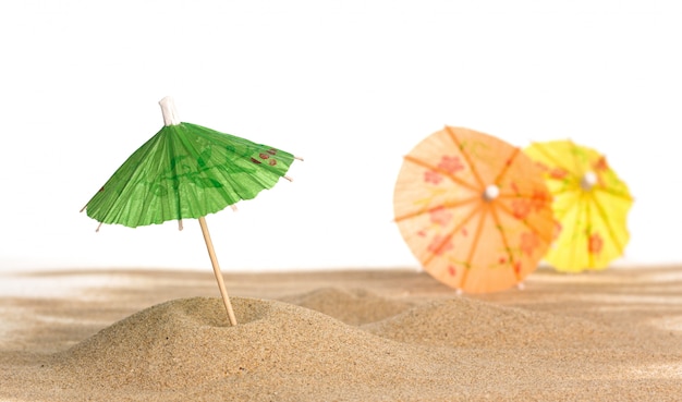 Cocktail guarda-chuva na areia no fundo branco