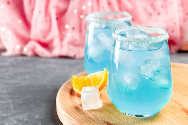 Cocktail mit Eis und blauem Curaçao auf einem zarten Rosa