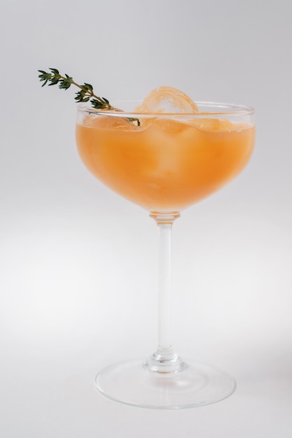 Cocktail mit Eiskruste und Orangenlikör in einem hohen, mit Rosmarin verzierten Glas