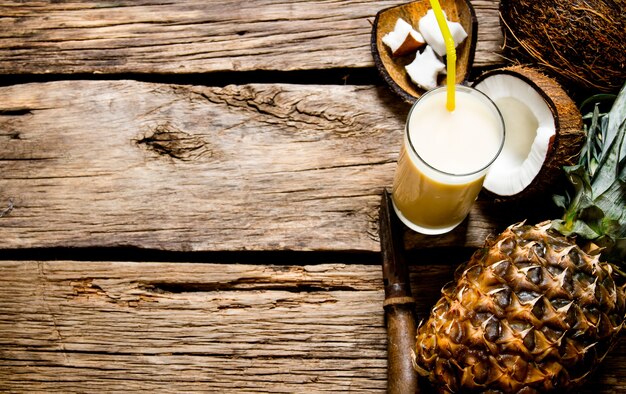 Cocktail Pina Colada. Frischer Cocktail mit Kokosnuss, Rum und Ananas auf einem Holztisch. Freier Platz für Text.