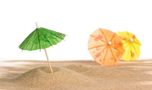 Cocktail Regenschirm im Sand auf weißem Hintergrund