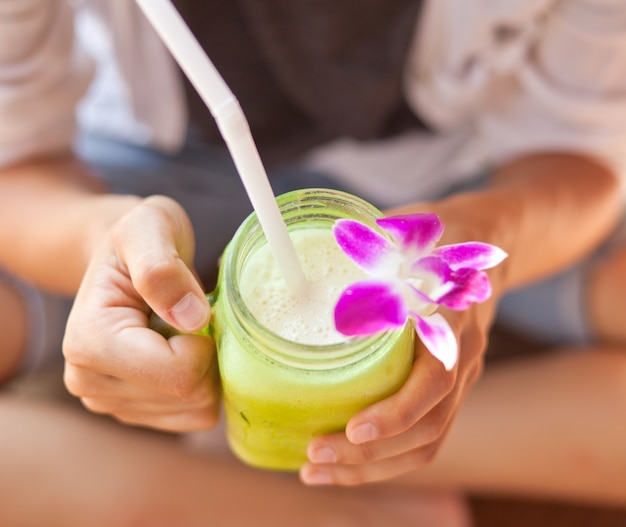 Cocktail Smoothie verziert mit Orchidee in den Händen von Frauen