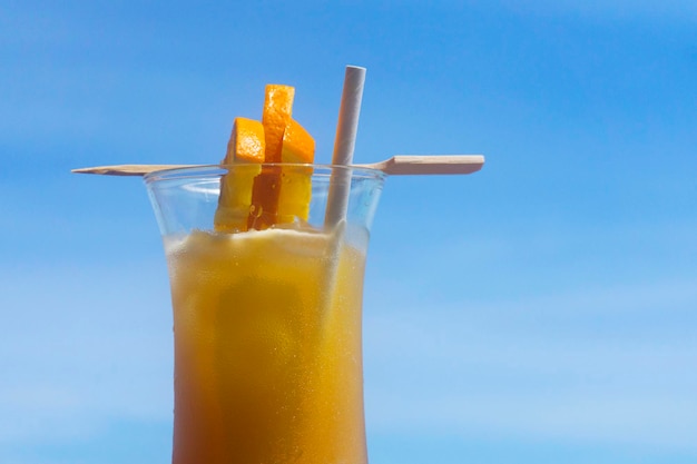 Cocktail tropical com laranja contra o céu azul