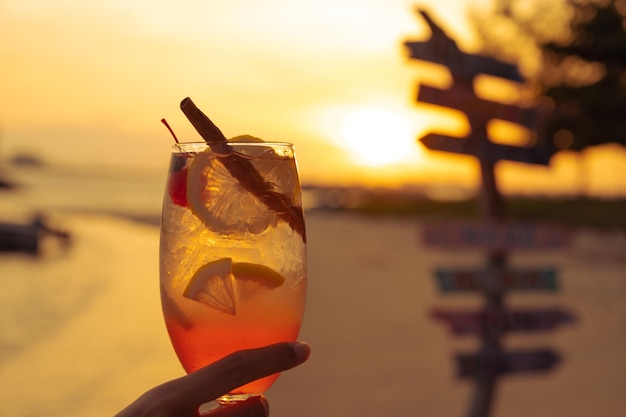 Cocktail tropical com pôr do sol sobre o mar ao fundo, viagem de férias de verão