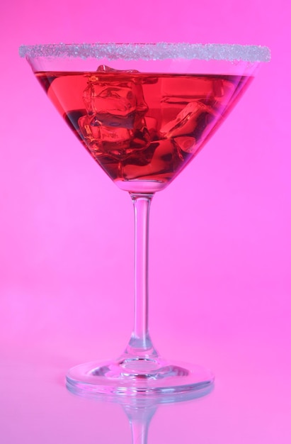 Cocktail vermelho no copo de martini no fundo rosa