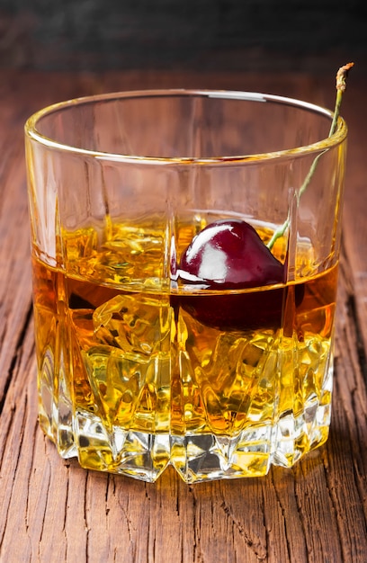 Cocktail vom Whisky mit Kirsche im Glas