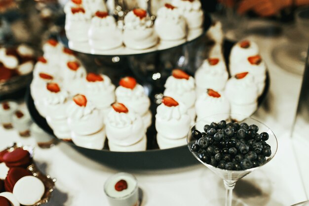 Cocktailglas mit Blaubeeren steht vor müdem Teller mit weißen Kuchen