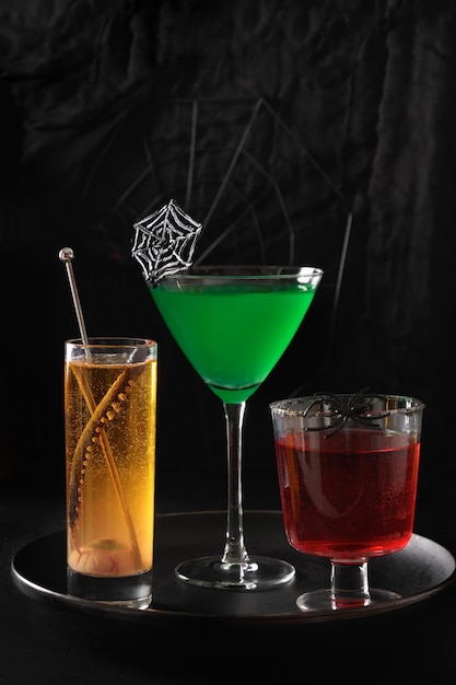 Cocktails verdes e laranja vermelhos de Halloween decorados teia de aranha e aranha