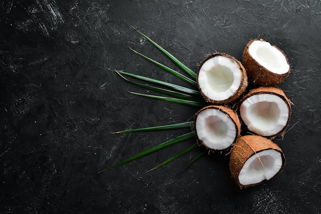 Coco com folhas de palmeira em um fundo de pedra preta Frutas tropicais Porca Vista superior Espaço livre para o seu texto