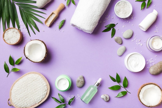 Coco com frascos de óleo de coco e creme cosmético em fundo colorido Vista superior Espaço livre para o seu texto Cosméticos naturais de coco de spa e conceito de tratamento orgânico Composição de spa de coco