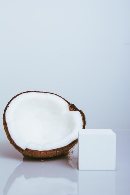 Coco cortado ao meio no fundo branco com reflexão e adereços para o produto