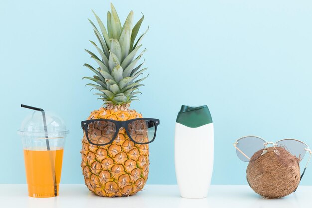 Coco de abacaxi fresco com óculos de sol e coquetéis garrafa de creme na cor de fundo
