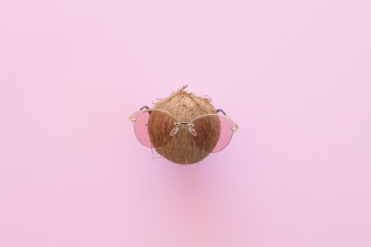 Coco fresco con gafas de sol sobre un fondo rosa brillante Hola verano