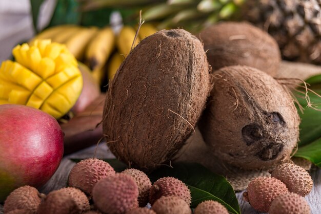 Coco y frutas exóticas sobre fondo de madera. Enfoque selectivo de fondo borroso.