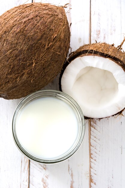 Coco y leche de coco en la mesa de madera blanca