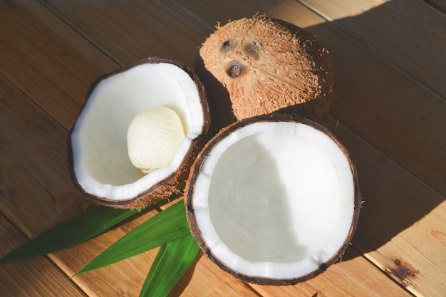 Coco con la mitad y hojas sobre fondo de madera