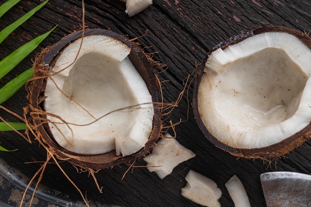 Coco picado sobre un fondo de madera, vista superior. La leche de coco y las hojuelas de coco son alimentos tropicales.