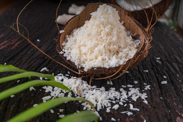 Coco picado sobre un fondo de madera, vista superior. La leche de coco y las hojuelas de coco son alimentos tropicales.