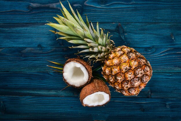 Coco y piña sobre un fondo de madera Frutas tropicales y nueces Vista superior Espacio libre para texto