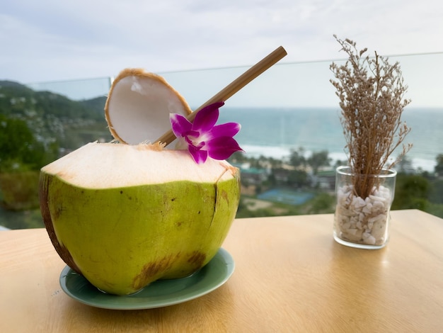 Foto coco verde fresco na mesa do restaurante com excelentes vistas da praia de kata noi em phuket, tailândia