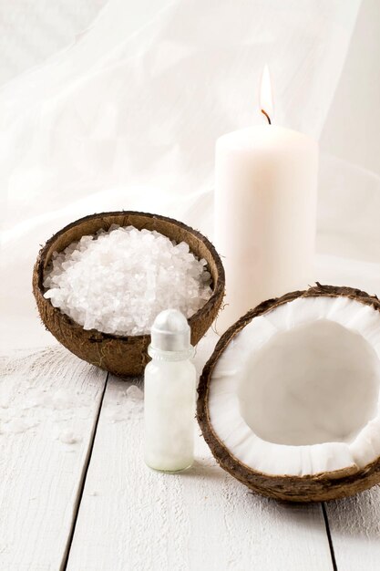 Coconut Spa-Zusammensetzung: Meersalz, Kokosnuss, Kokosnussöl und eine Kerze mit Kokosduft auf weißem Hintergrund. Selektiver Fokus