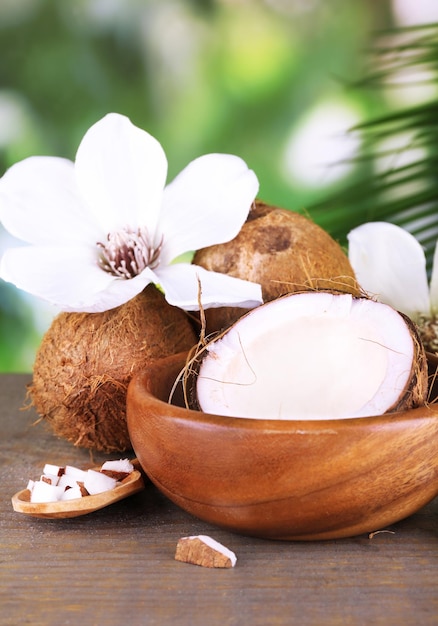 Cocos y aceite de coco en la mesa de madera sobre fondo de naturaleza