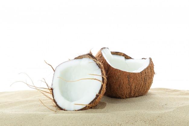 Cocos en la arena de mar clara aislada en el fondo blanco. Vacaciones de verano