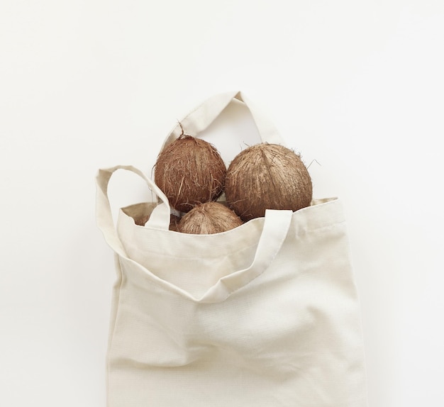Cocos en una bolsa de algodón reutilizable sobre un fondo blanco Concepto de cero residuos sin plástico