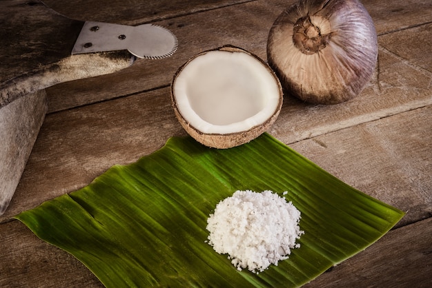 Cocos e flocos de coco na folha de bananeira e ralador de coco