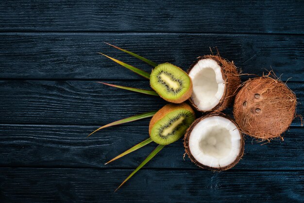Cocos y kiwi sobre un fondo de madera Frutas tropicales y nueces Vista superior Espacio libre para texto