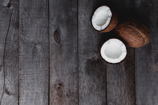 Cocos quebrados em fundo cinza de madeira. Polpa de coco branca. Foto de alta qualidade