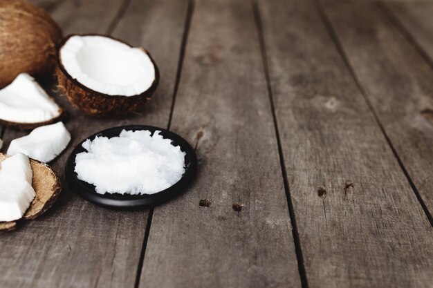 Cocos quebrados na superfície de madeira cinza. polpa fresca de coco branco na placa preta.