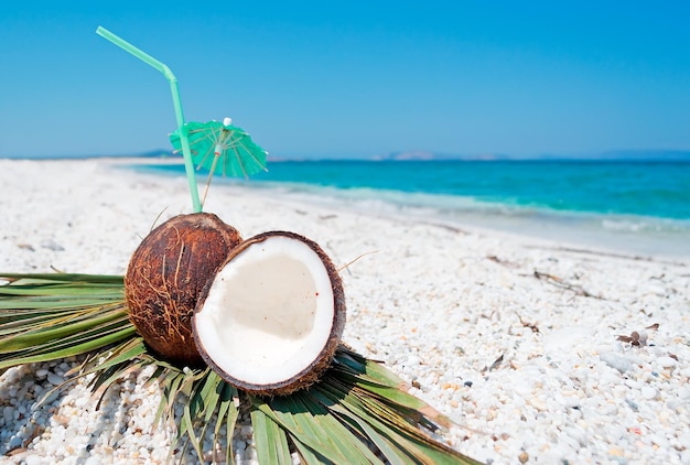 Cocos con sombrilla y paja en la orilla