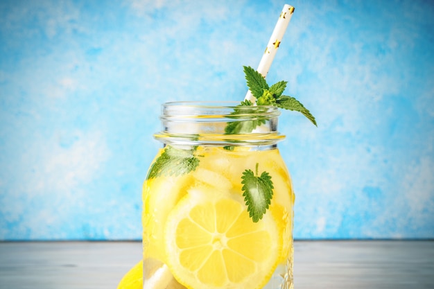 Coctail-Glas Limonade und tadellose Blätter auf blauem Hintergrund des Holztischs