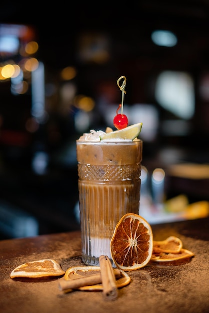 Cóctel adornado con naranja seca y cereza en el mostrador del bar El concepto de la correcta preparación de bebidas