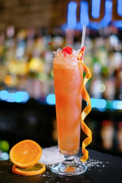 Cóctel adornado con naranja seca y cereza en el mostrador del bar El concepto de la correcta preparación de bebidas