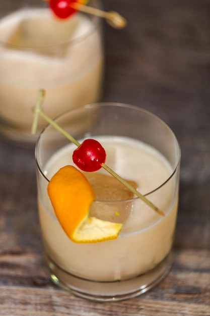 Cóctel agrio de whisky adornado con naranja y cereza.