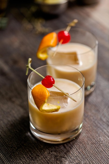 Cóctel agrio de whisky adornado con naranja y cereza.