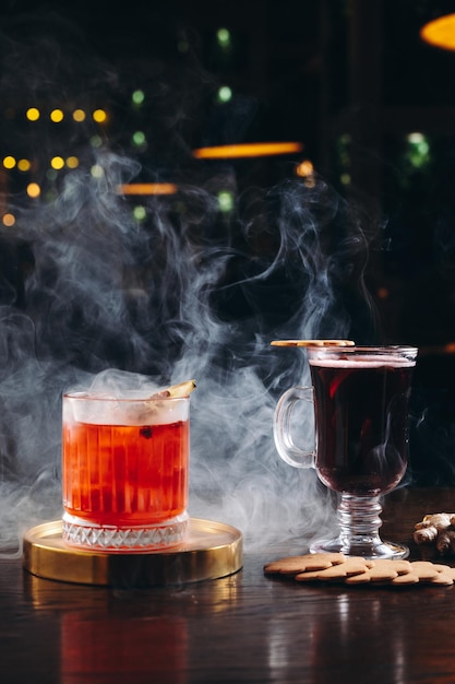 Foto cóctel ahumado a la antigua y vino caliente sobre la mesa sobre fondo oscuro