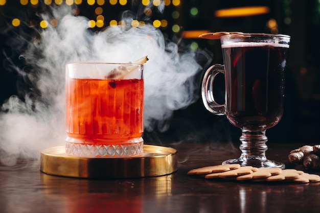 Foto cóctel ahumado a la antigua y vino caliente sobre la mesa sobre fondo oscuro