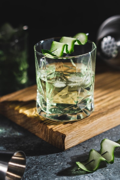 Cóctel de alcohol con pepino en vaso de whisky con cubitos de hielo Bebida espirituosa de verano y agitador