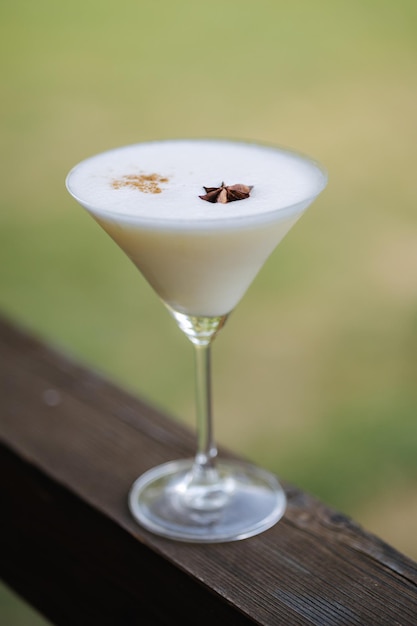 Cóctel alcohólico blanco con champagne limonada o Martini con espuma y decorado con anís estrellado