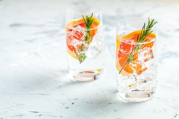 Cóctel alcohólico con ginebra de hielo de soda de pomelo y mesa de hormigón gris claro de romero