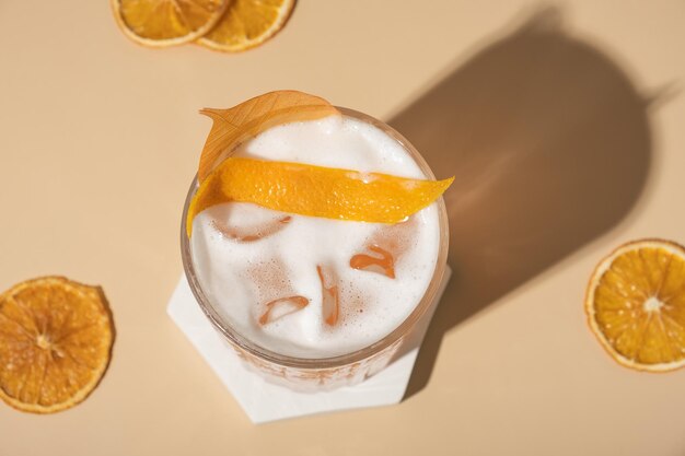 Cóctel alcohólico con hielo y espuma con naranja seca vista desde arriba