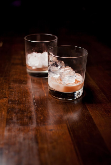 Cóctel alcohólico de moda con vodka, licor de café, crema y hielo sobre fondo oscuro.