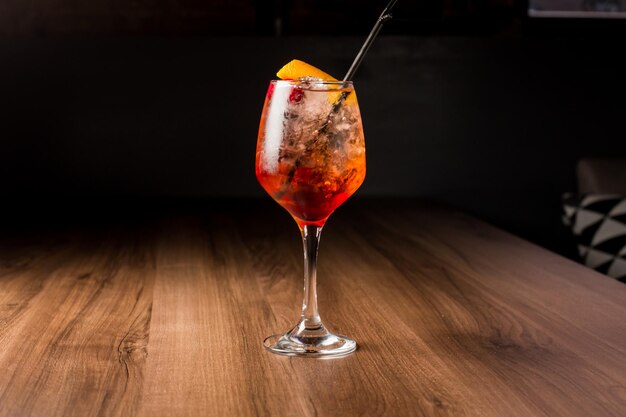 Cóctel alcohólico de naranja Aperol Spritz con cáscara de naranja de cerezas sobre un fondo oscuro