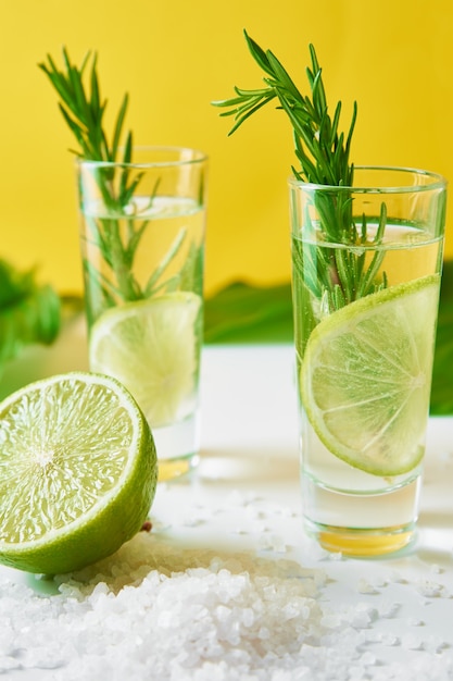 Cóctel alcohólico de verano. Refresco refresco de limón. Gin tonic con lima y romero sobre fondo amarillo