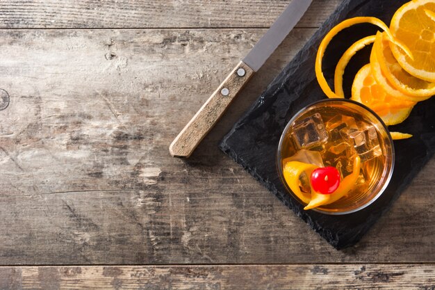 Cóctel antiguo con naranja y cereza en la mesa de madera Vista superior copia espacio