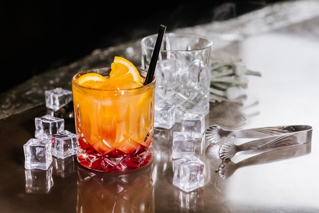 Cóctel de aperol naranja con hielo sobre fondo oscuro