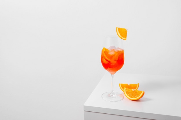 Cóctel Aperol Spritz en vaso con hielo y naranja sobre fondo blanco.